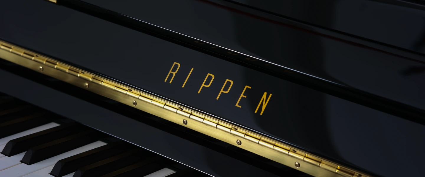 Gold RIPPEN lettering and brass hinge detail on a black piano cabinet